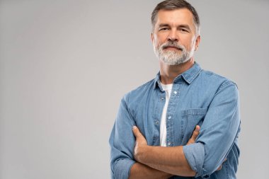 Beyaz arka planda duran gülümseyen olgun bir adamın portresi.