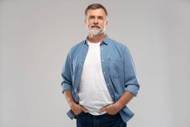 Beyaz arka planda duran gülümseyen olgun bir adamın portresi.