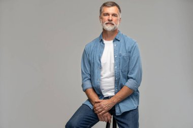 Beyaz arka planda bir sandalyede oturan son sınıf öğrencisinin portresi.