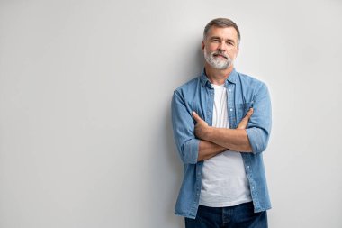 Beyaz arka planda duran gülümseyen olgun bir adamın portresi.