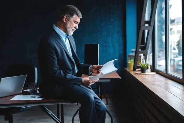 Zelfverzekerde penetrante volwassen zakenman in modern kantoor. — Stockfoto