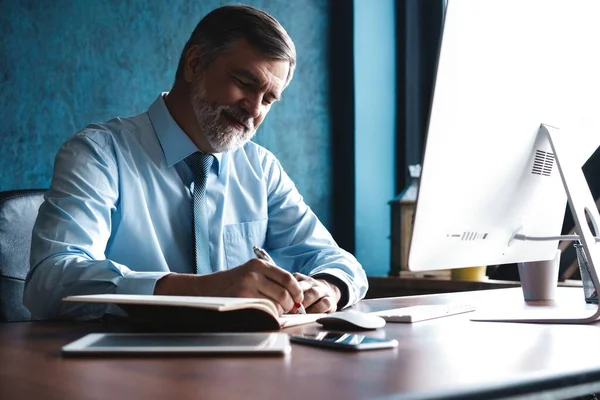 Volwassen zakenman op zoek en analyseren van document in zijn moderne kantoor op het werk. — Stockfoto