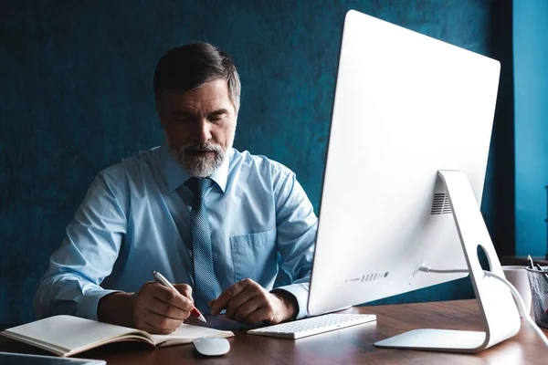 Volwassen zakenman op zoek en analyseren van document in zijn moderne kantoor op het werk. — Stockfoto