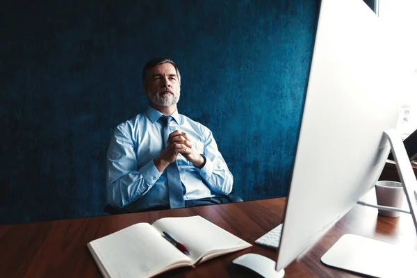 Gerichte volwassen zakenman diep in gedachte terwijl zittend aan een tafel in modern kantoor. — Stockfoto