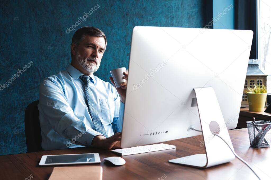 Mature Businessman Working On Computer In Office
