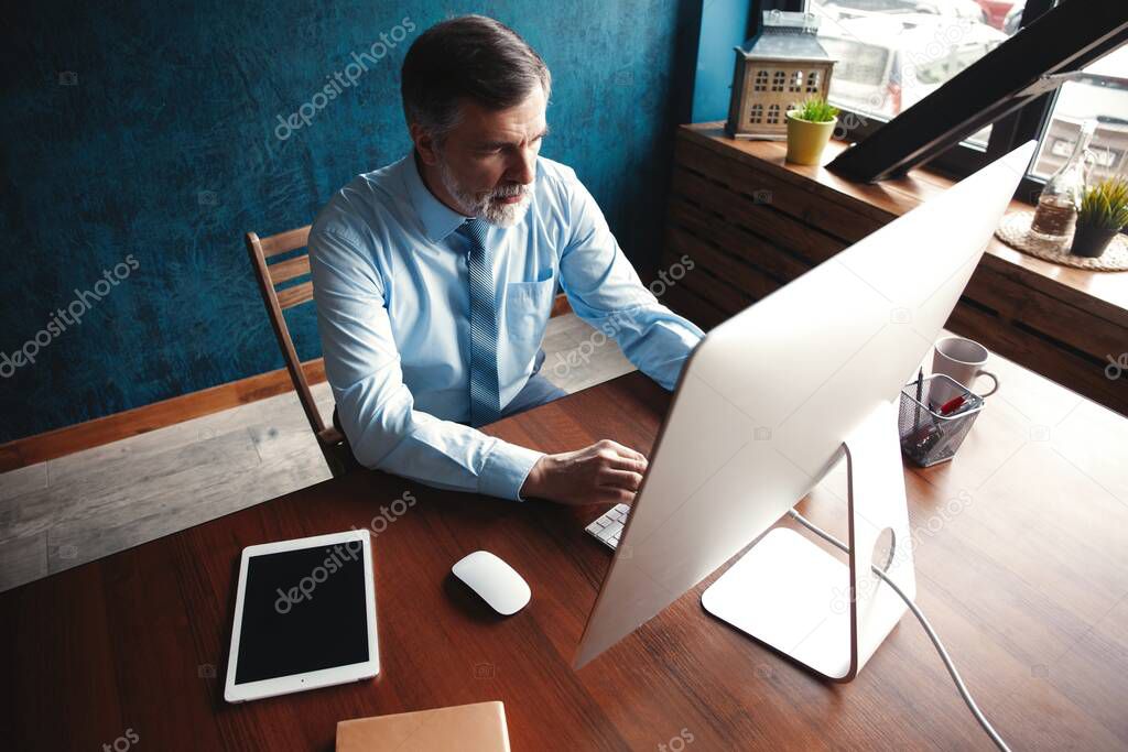 Mature Businessman Working On Computer In Office