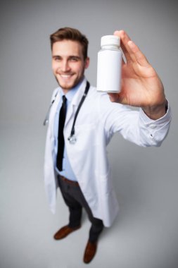 Gülen doktor elinde bir kutu hap ya da ilaç tutuyordu. Hastalık veya yaralanma tedavisi için beyaz etiketli..