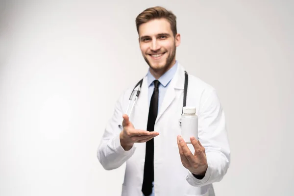 Médecin souriant tenant un flacon de comprimés ou de pilules avec une étiquette blanche vierge pour le traitement d'une maladie ou d'une blessure. — Photo