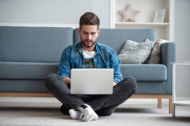 İnternette çalışan yakışıklı modern erkek tasarımcı, evde internet kullanıyor.