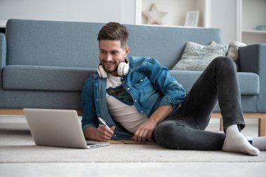 İnternette çalışan yakışıklı modern erkek tasarımcı, evde internet kullanıyor.