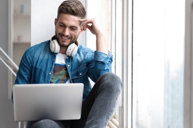 İnternette çalışan yakışıklı modern erkek tasarımcı, evde internet kullanıyor.