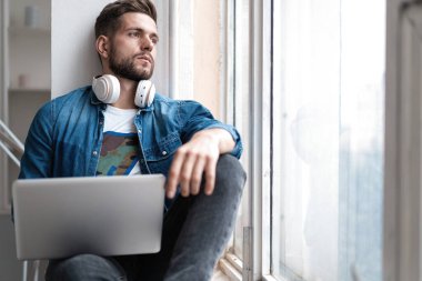 İnternette çalışan yakışıklı modern erkek tasarımcı, evde internet kullanıyor.