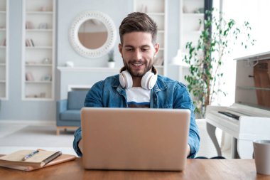 İnternette çalışan yakışıklı modern erkek tasarımcı, evde internet kullanıyor.