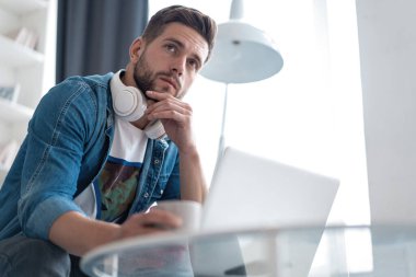 İnternette çalışan yakışıklı modern erkek tasarımcı, evde internet kullanıyor.