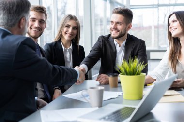 İş adamları yaratıcı ofiste çalışırken el sıkışıyorlar.