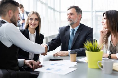 İş adamları yaratıcı ofiste çalışırken el sıkışıyorlar.