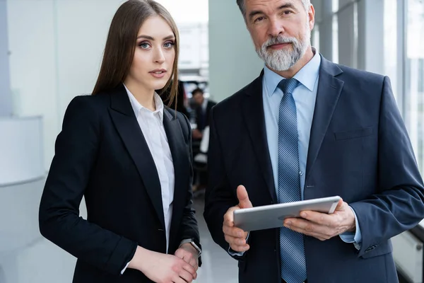 Affärsmän som står på kontoret och tittar på en tablett. — Stockfoto