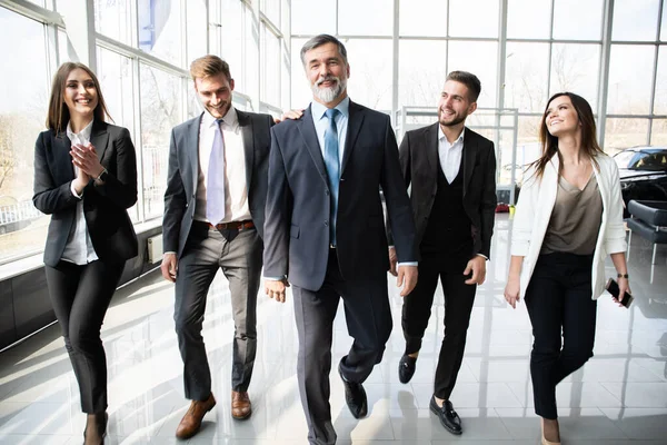 Команда ділових людей, що йдуть в сучасному офісі, впевнені бізнесмени та ділові жінки зі зрілим лідером уперед . — стокове фото