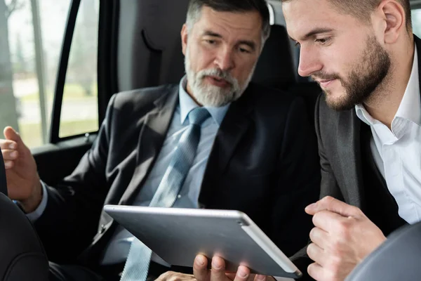 Collègues d'affaires discuter des idées d'affaires tout en étant assis sur le siège arrière de la voiture ou un taxi. — Photo