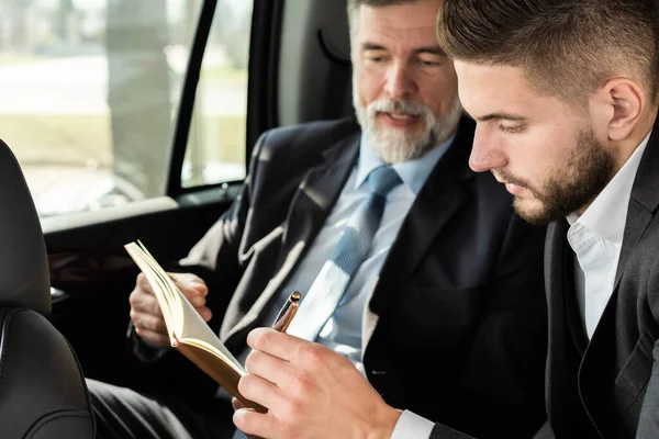 Colegas de negocios discutiendo ideas de negocios mientras están sentados en el asiento trasero del coche o taxi . —  Fotos de Stock