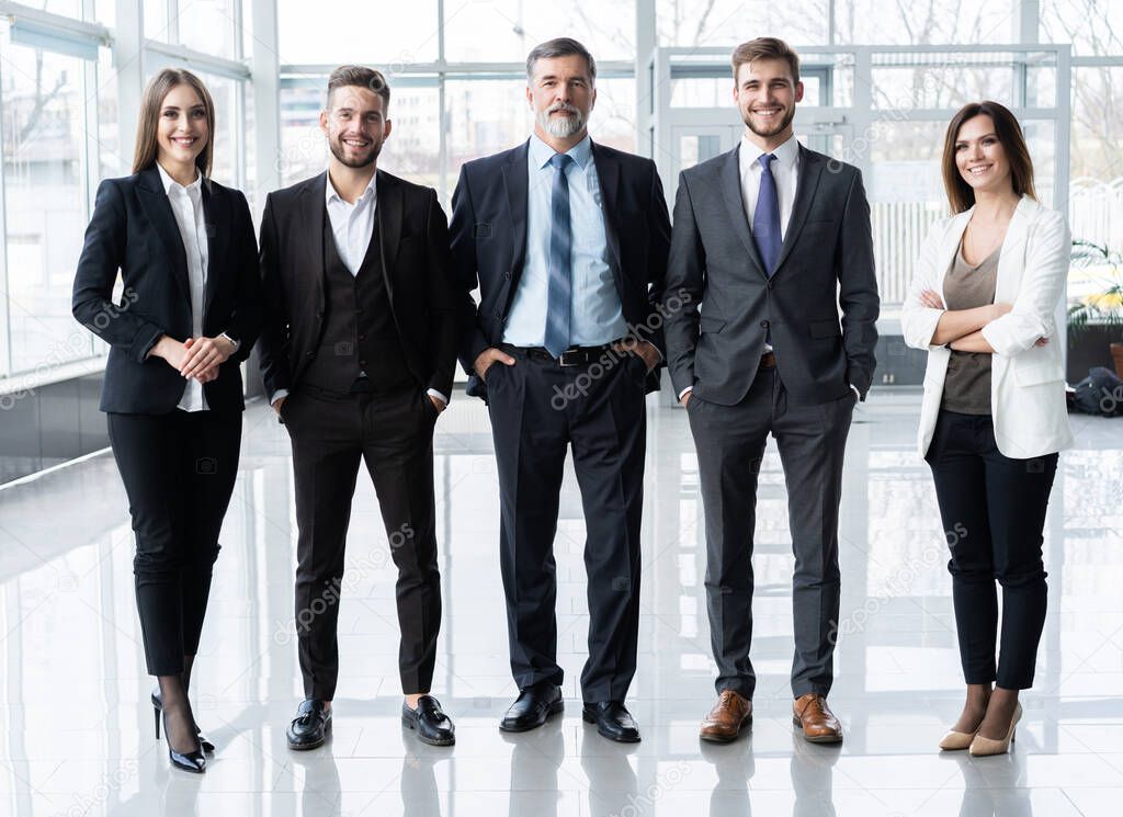 Full length confident business team stands in office.