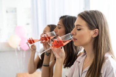 Pijama partisi. Çekici, pijamalı, gülümseyen kadınlar yatak odasında pijama partisi yaparken şampanya içiyorlar..