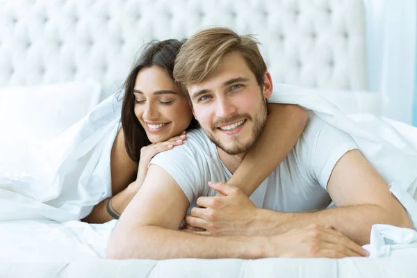 Junges glückliches Paar liegt zusammen im Bett. — Stockfoto