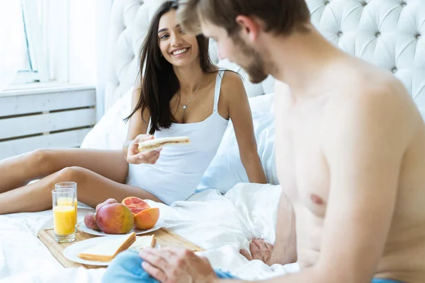 健康的早餐在床上。年轻漂亮的情侣们在吃早饭前正坐在床上. — 图库照片