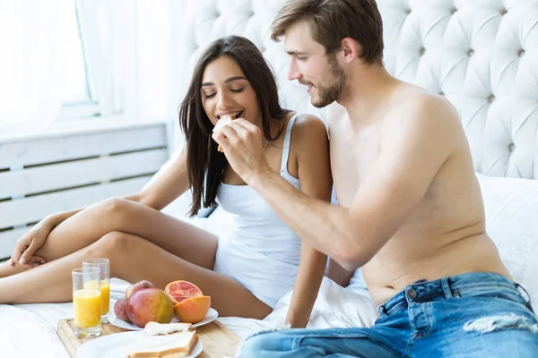 Healthy breakfast in bed. Young beautiful love couple is sitting in bed before having breakfast.