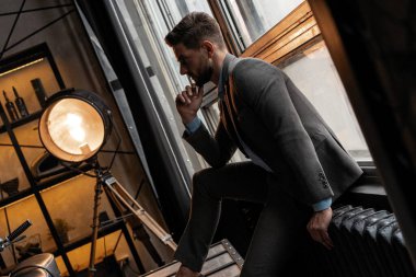 Genç ve kendinden emin. Pencerede oturan yakışıklı genç adam.