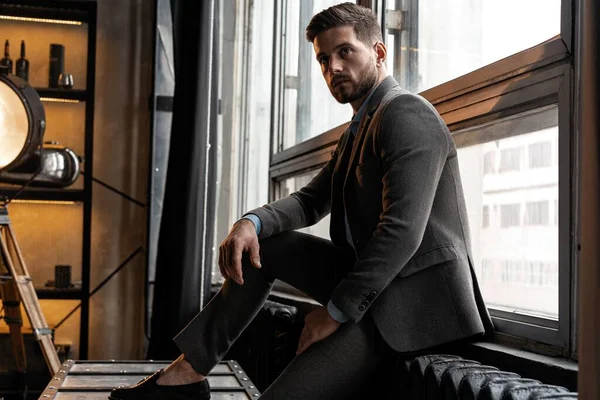 Young and confident. Handsome young man sitting on window. — Stock Photo, Image