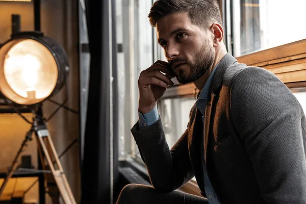 Young and confident. Handsome young man sitting on window. — Stock Photo, Image