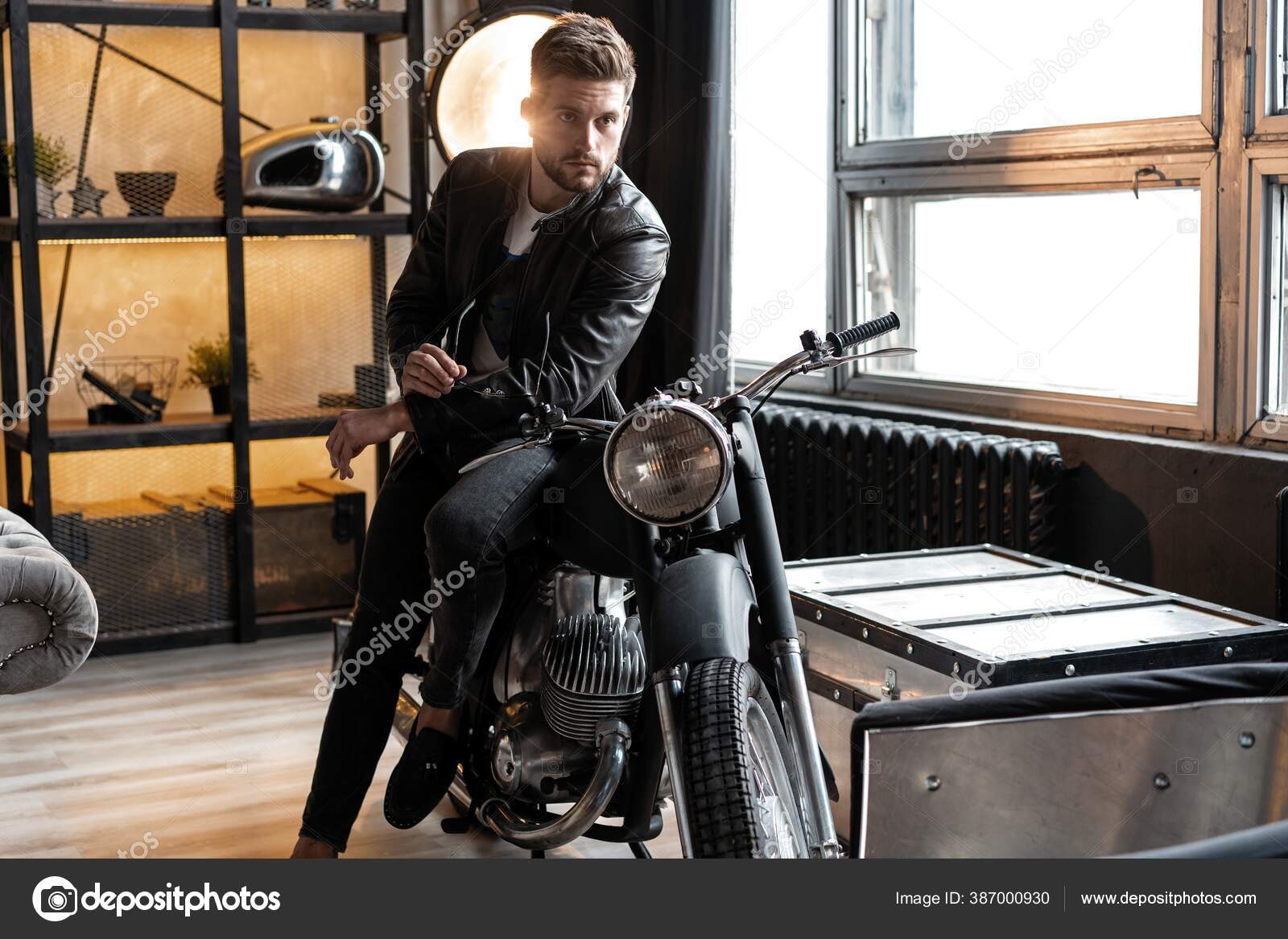 Hombre joven con estilo en chaqueta de cuero sentado en moto