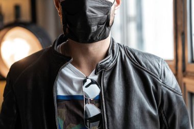 Koronavirüs COVID-19 'dan korunmak için koruyucu maskeli genç bir adam. Kişisel koruma.