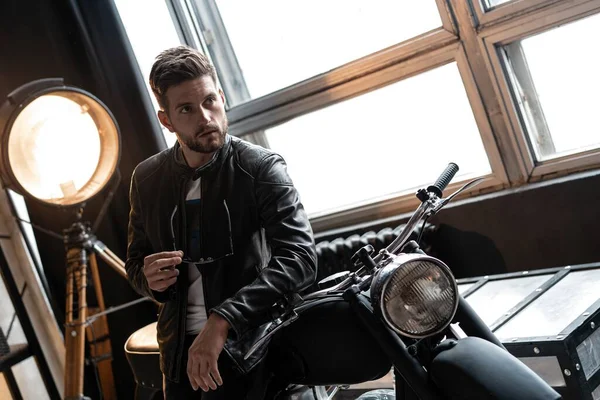 穿着皮夹克坐在摩托车上的时髦年轻人. — 图库照片