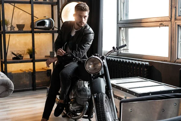 Stylish young man in leather jacket sitting on motorbike. — Stock Photo, Image