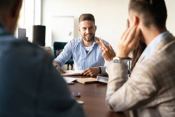 Grupo de jovens empresários que trabalham e se comunicam enquanto se sentam na mesa do escritório juntos — Fotografia de Stock