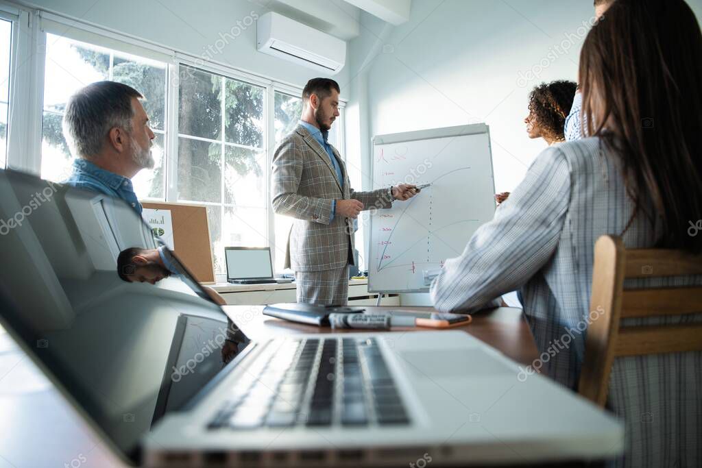 Business man making a presentation at office. Business executive delivering a presentation to his colleagues during meeting or in-house workshop.