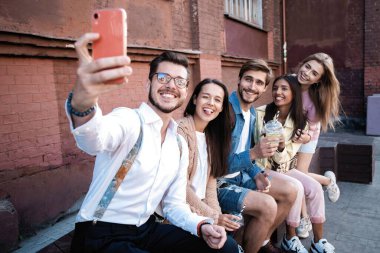 Yaz, tatiller, tatil ve mutluluk konsepti. Bir grup arkadaş akıllı telefondan selfie çekiyor.