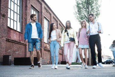 Bir grup mutlu genç arkadaş birlikte yürüyor, şehirde eğleniyorlar..
