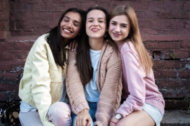 Sokakta poz veren üç güzel gülümseyen hippi kızın portresi. Pozitif modeller sakızla eğleniyor ve balon üflüyor