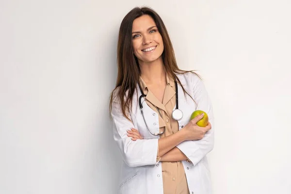 의사인 여자는 청진기를 미소를 사과를 배경때문에 고립됨 — 스톡 사진