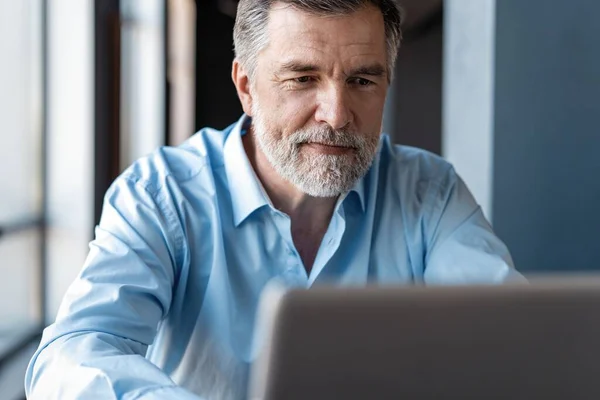 Gammal affärsman som jobbar på laptop. Snygg mogen företagsledare som sitter på ett modernt kontor — Stockfoto