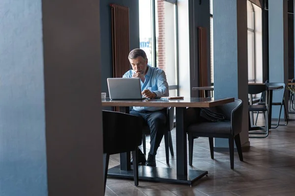 Hombre de negocios maduro trabajando en el portátil. Guapo líder de negocios maduro sentado en una oficina moderna — Foto de Stock