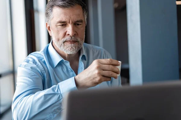 Volwassen zakenman werkt aan een laptop. Knappe volwassen business leader zittend in een modern kantoor — Stockfoto