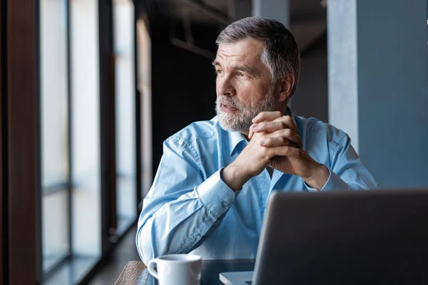 Volwassen zakenman werkt aan een laptop. Knappe volwassen business leader zittend in een modern kantoor — Stockfoto