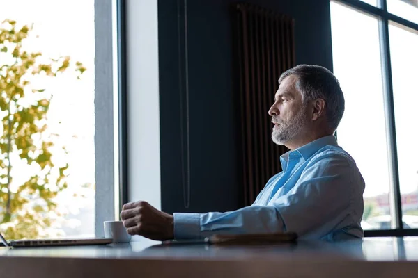 Hombre de negocios pensativo bebiendo café en la cafetería y mirando hacia otro lado . — Foto de Stock