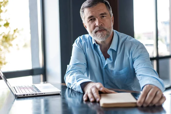 Zakenman zit in een business center restaurant, op zoek naar documenten. — Stockfoto