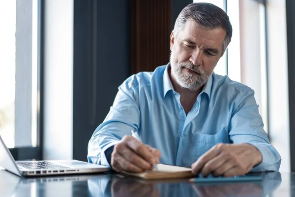 Zakenman zit in een business center restaurant, op zoek naar documenten. — Stockfoto