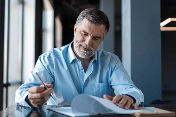 Empresario sentado en un restaurante del centro de negocios, mirando a través del contrato . — Foto de Stock